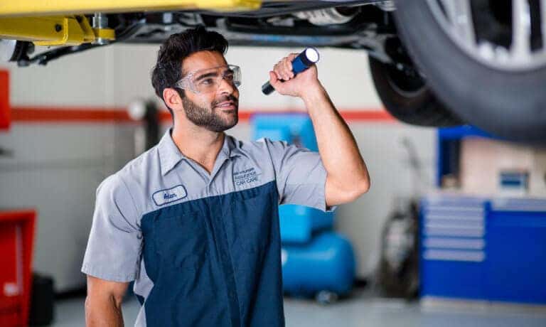 Hyundai technician checking under a vehicle with a flashlight