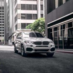 BMW white vehicle driving down street.