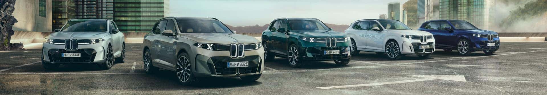 Panoramic view of five BMW X5 and iX5 models showcasing different powertrain options parked outside.