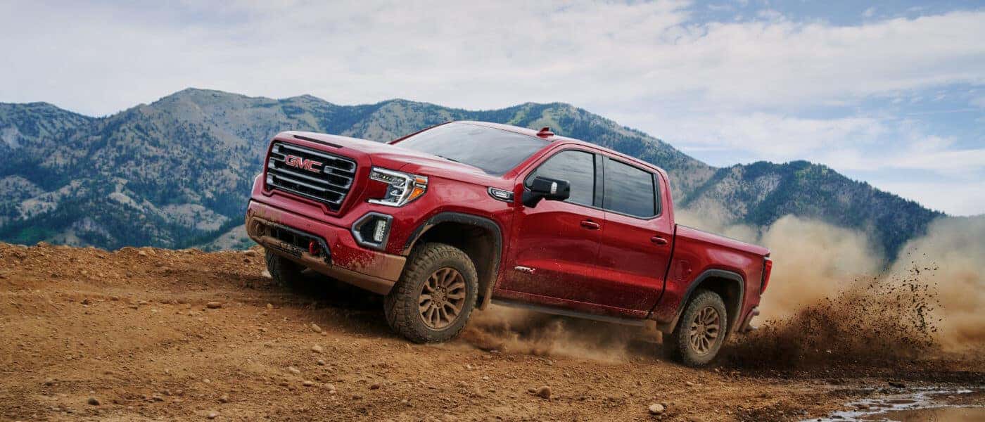 GMC Sierra 1500 in red exterior driving above dirt road