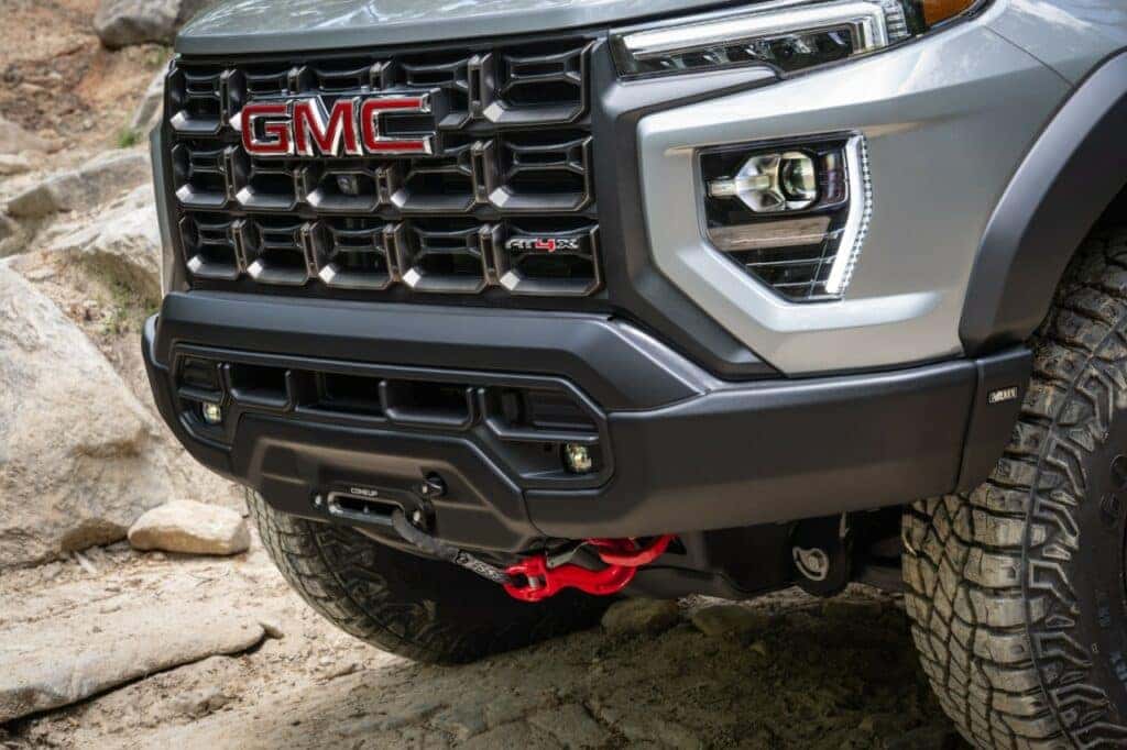Lower shot of the 2024 GMC Canyon AT4X AEV’s stamped steel front bumper and red recovery hooks.