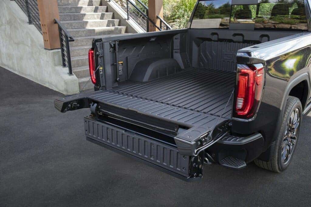 2024 GMC Sierra Denali Ultimate 1500 Crew Cab Short Box in Titanium Rush Metallic, showing CarbonPro Bed and MultiPro Tailgate; 3/4 passenger-side rear view.