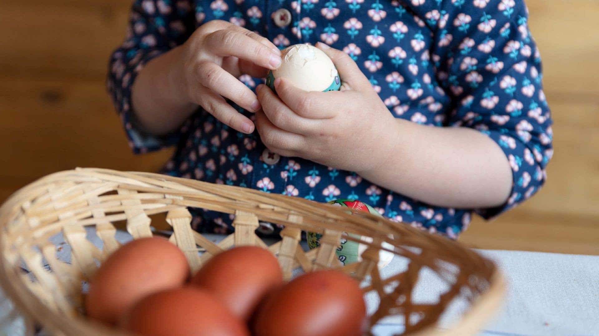 A Child Taking A White Egg Out Of A Basket Of Brown Eggs And Cracking It To Make A Healthy Snack With Their Parents