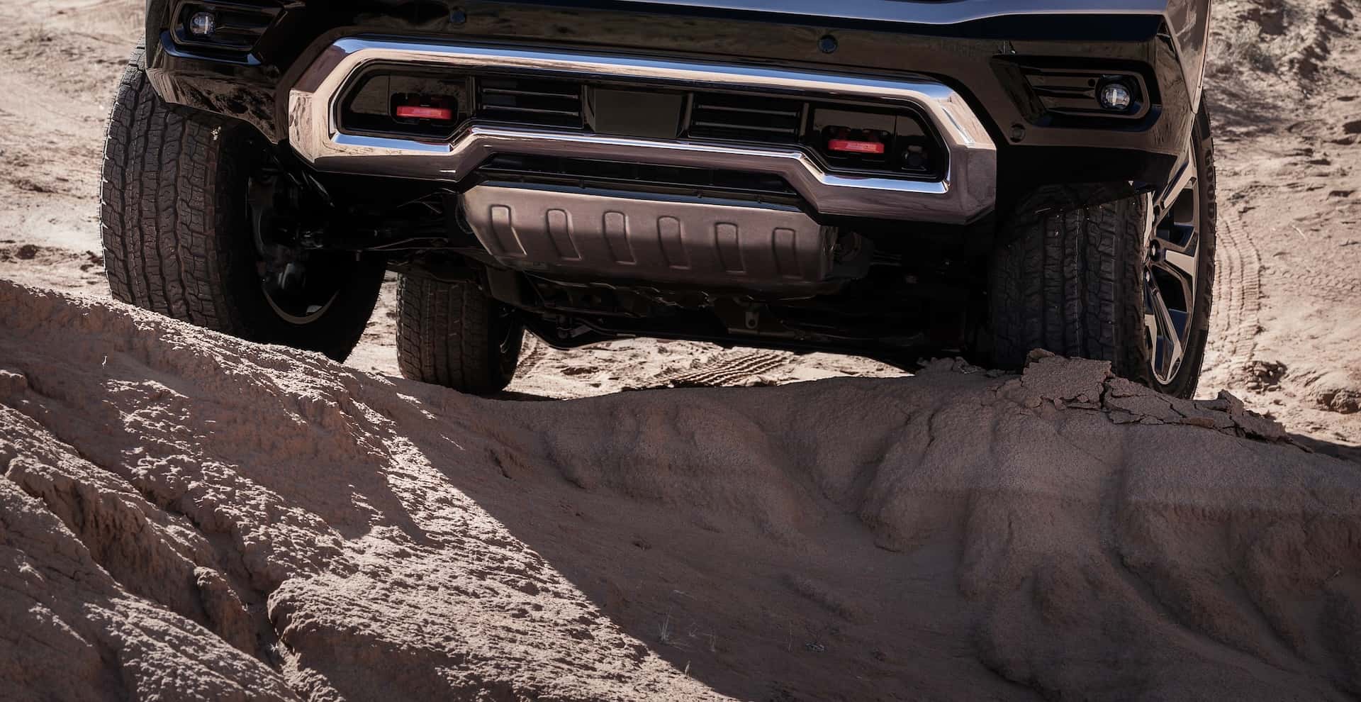 Underbody view of the 2025 GMC Yukon AT4 Ultimate featuring a front skid plate and red recovery tow hooks.