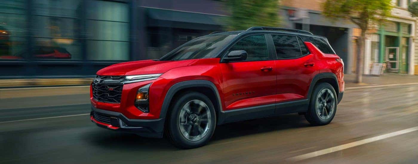 Red 2026 Chevy Equinox driving down a city street.