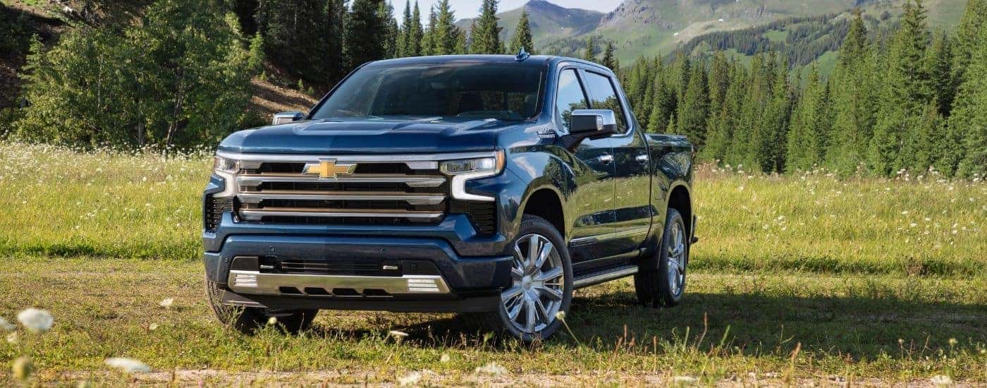 Blue 2022 Chevy Silverado 1500 High Country parked in a grassy field.