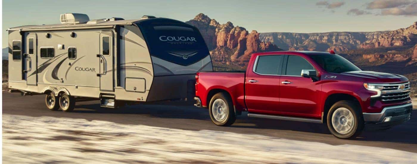 A red 2026 Chevy Silverado 1500 LTZ Z71 is towing a camper.