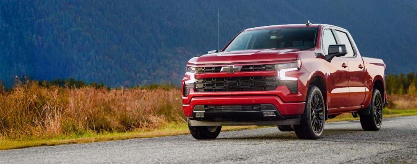 A red 2026 Chevy Silverado 1500 RST driving a grass-lined road.