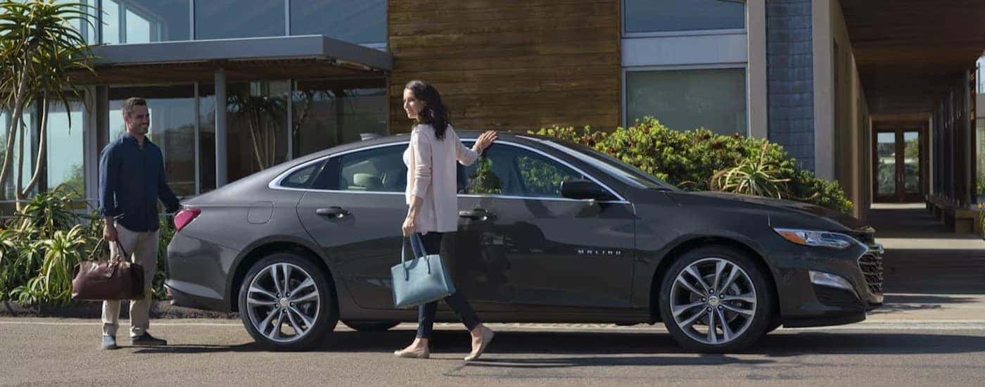 A gray 2024 Chevy Malibu parked near a buuilding.