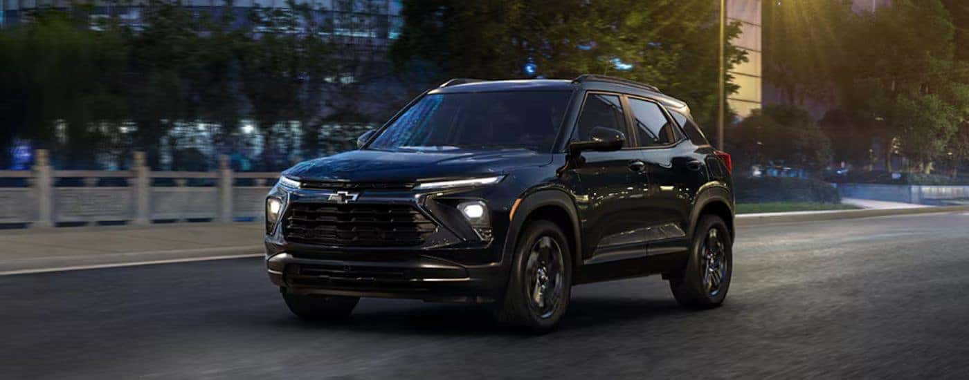 Black 2026 Chevy Trailblazer Midnight edition driving through a city in the evening.