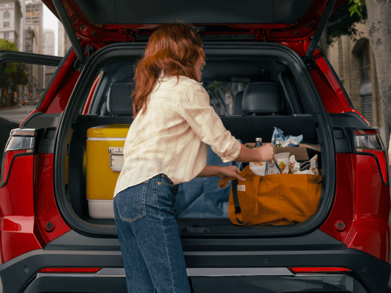 Person loading groceries into the rear cargo area of a Chevrolet SUV