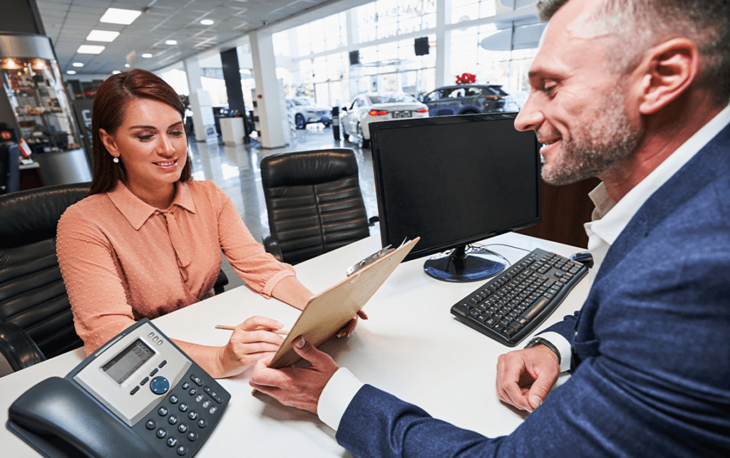 Why drivers should consider an extended warranty on their Chevrolet at Delaney Chevrolet of Greensburg | Sales person talking to customer at his desk inside of the dealership