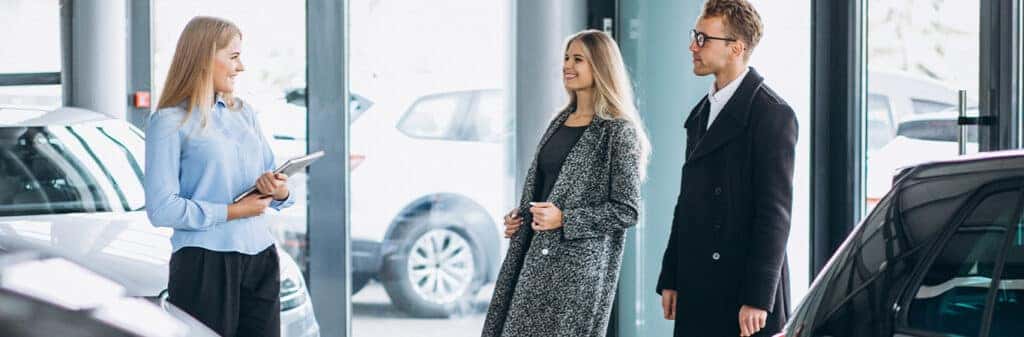 When to Trade In Your Car | Delaney Chevrolet of Greensburg in Greensburg, PA | Couple walking into a dealership while a sales person greets them