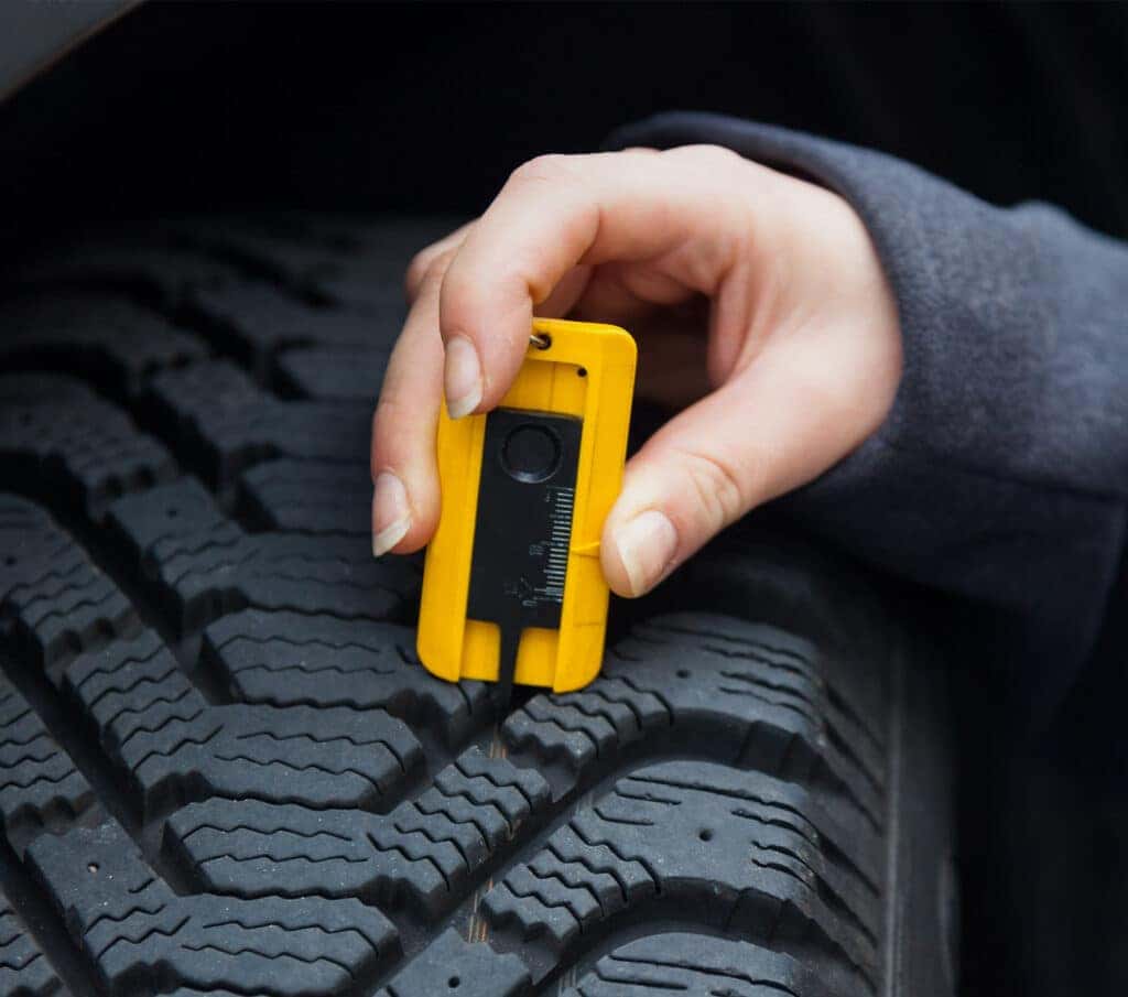 How to check your tires' health at Delaney Nissan of Greensburg | Persom using a tool to measure the depth of thier car tire