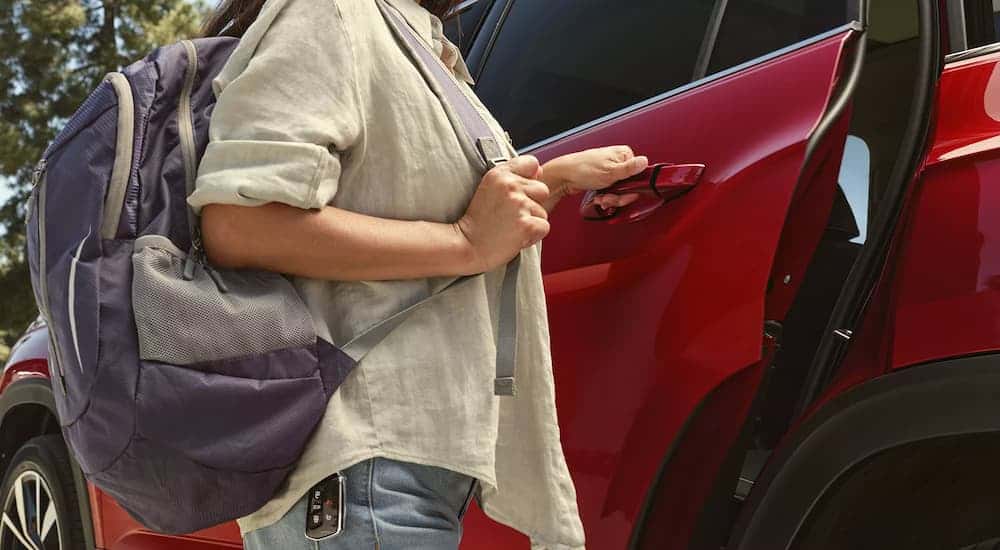 Woman opening door on a red 2025 Volkswagen Atlas R-Line at a Volkswagen dealer.