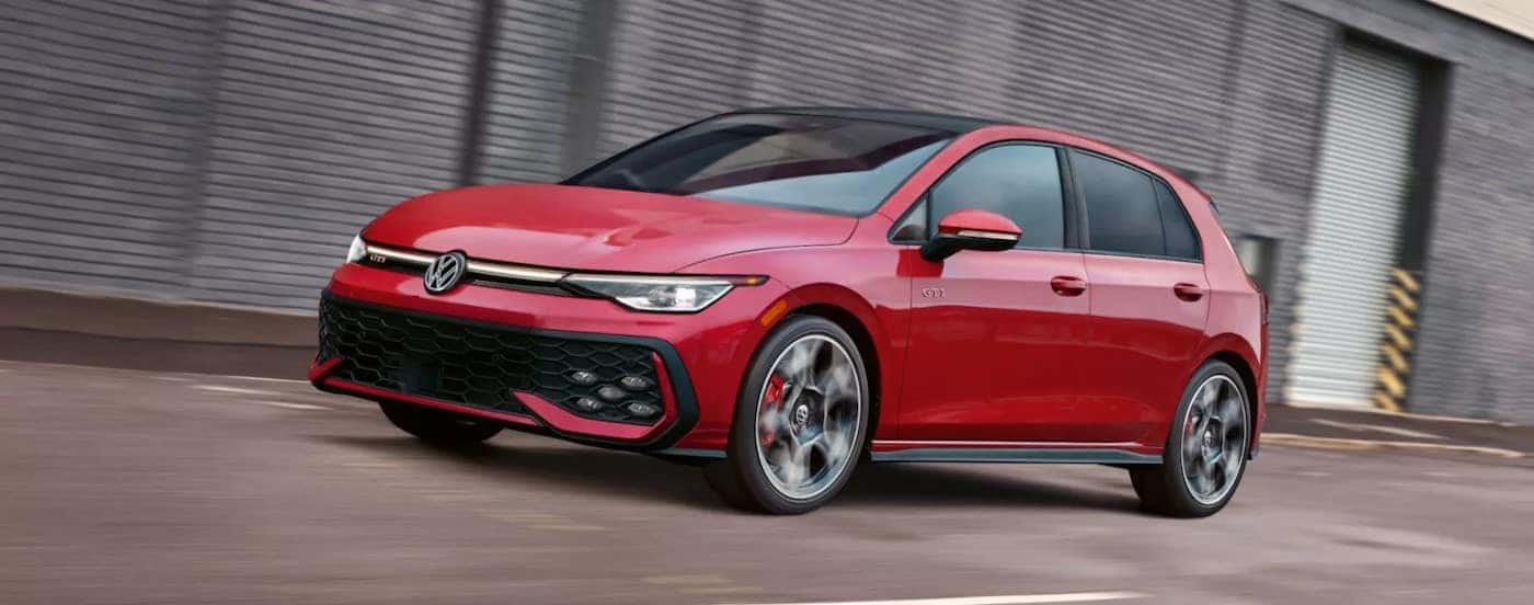 A red 2025 Volkswagen Golf GTI driving to a Volkswagen dealer near Schaumburg.