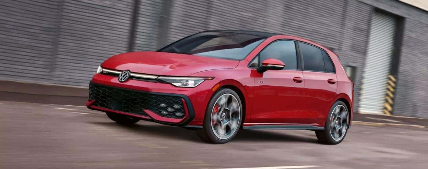 A red 2025 Volkswagen Golf GTI driving to a Volkswagen dealer near Huntley.