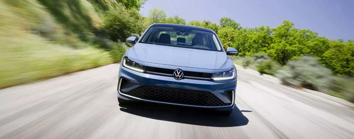 A blue 2025 Volkswagen Jetta driving on a highway.