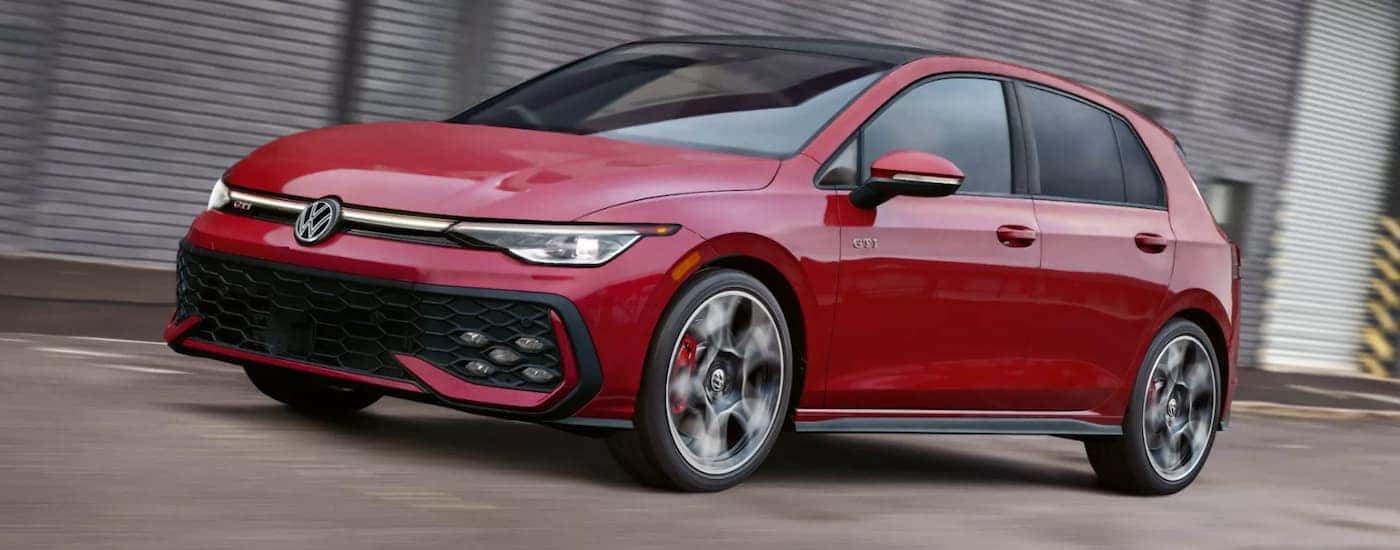 A red 2026 Volkswagen Golf GTI driving in a city