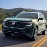 A green 2026 Volkswagen Atlas driving on a highway.
