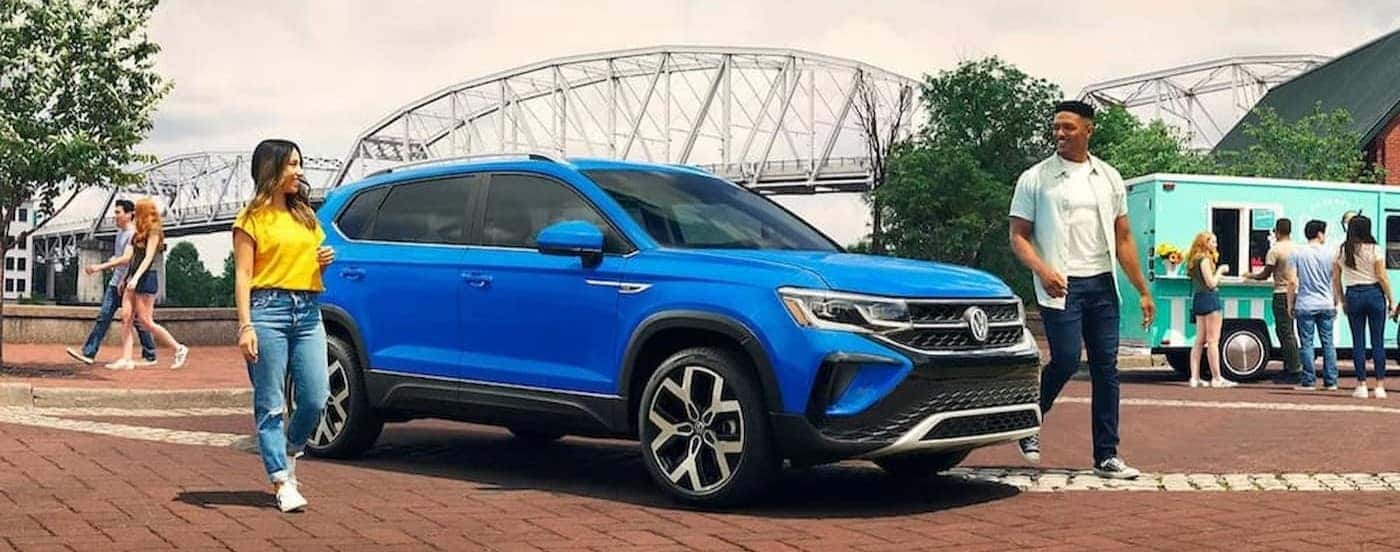 A blue 2023 Volkswagen Taos parked near a bridge.