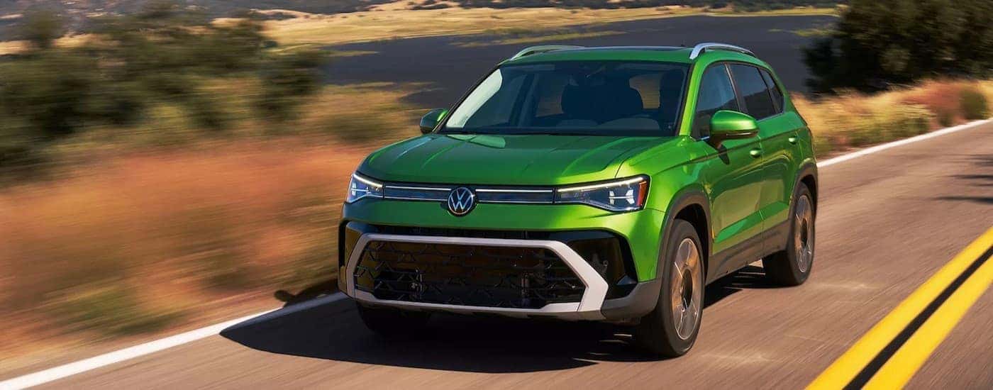 A green 2025 Volkswagen Taos driving on a highway.