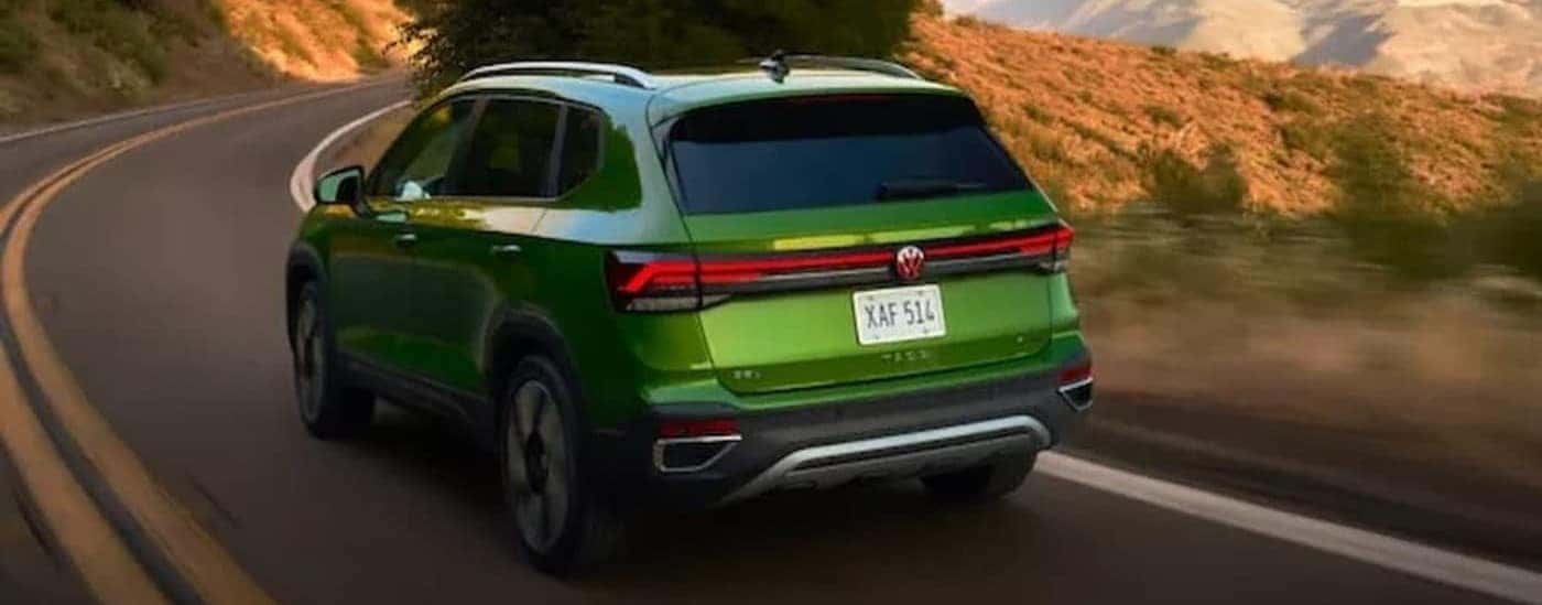 A green 2026 Volkswagen Taos for sale near Carpentersville driving on a highway.