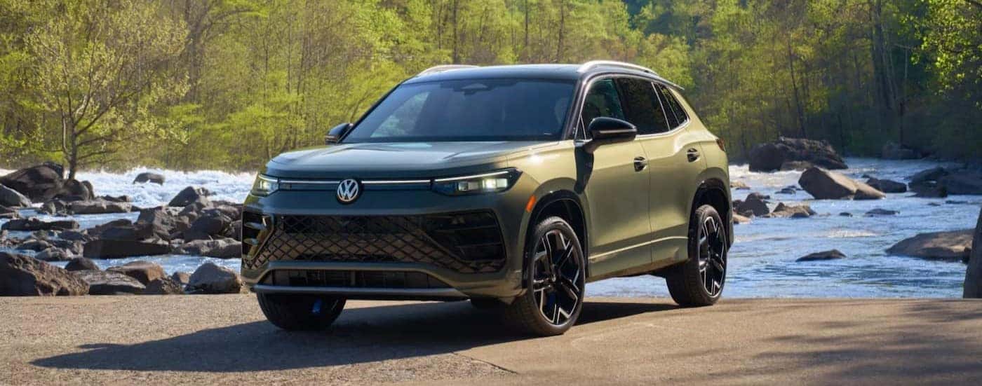 A green 2026 Volkswagen Tiguan parked near a stream.