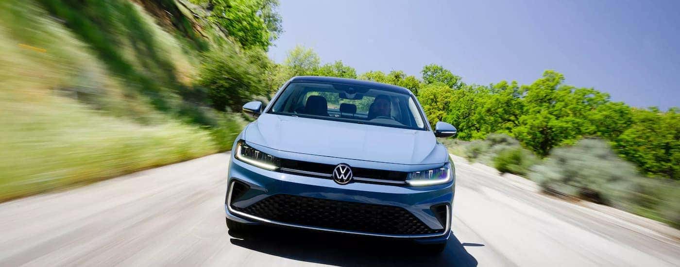 A blue 2026 Volkswagen Jetta driving down a highway