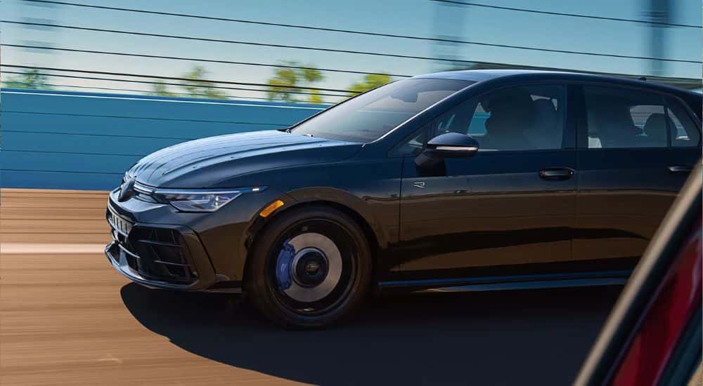 Black 2026 Volkswagen Golf R side view as it drives on a racetrack