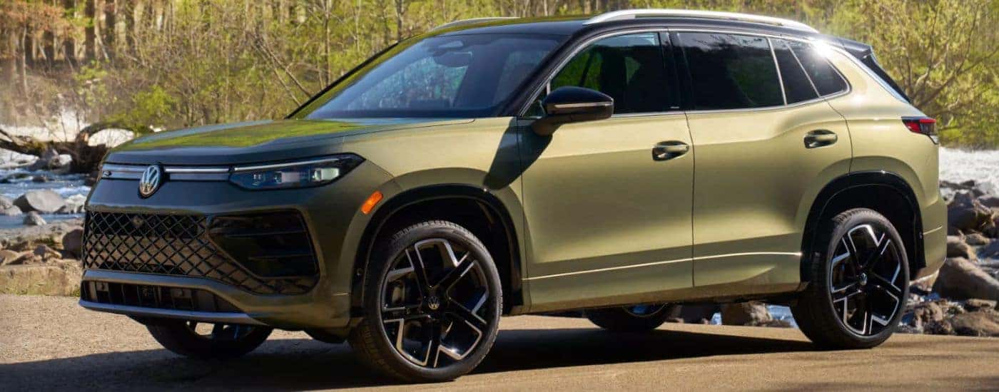 A green 2026 Volkswagen Tiguan is parked in front of a rocky river.