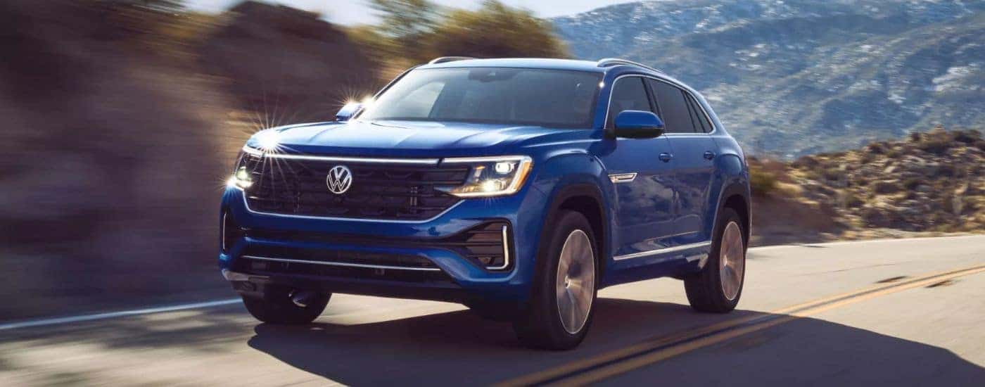 Blue 2026 Volkswagen Atlas Cross Sport driving on a road.