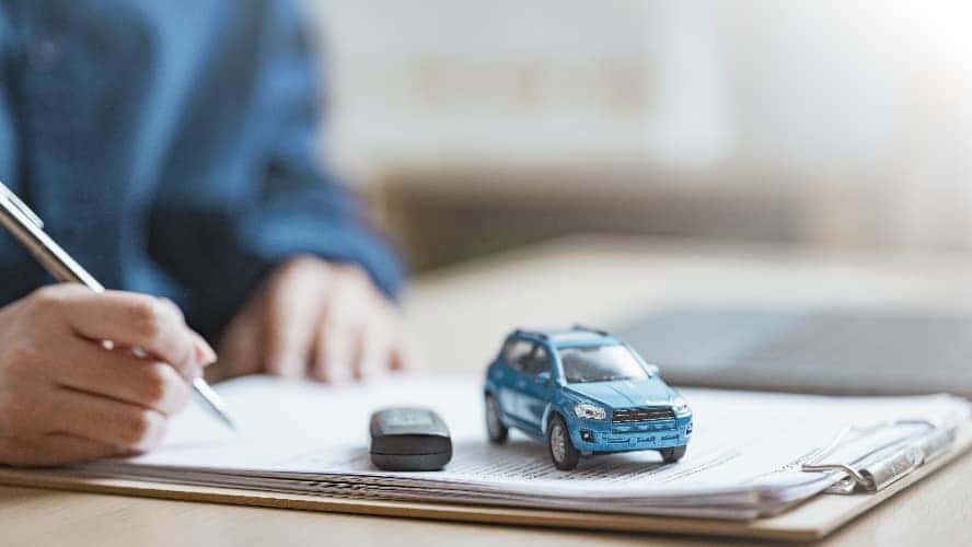 A person signing an auto loan agreement.