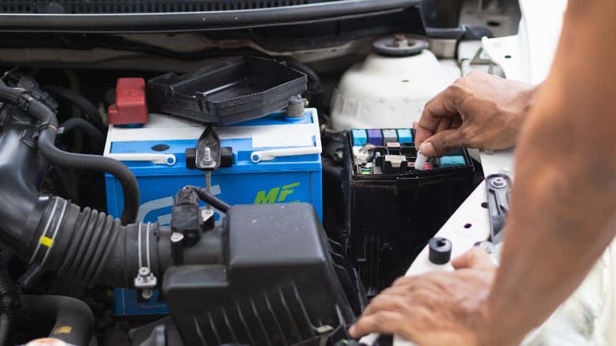 A mechanic examining the components under a vehicle's hood.