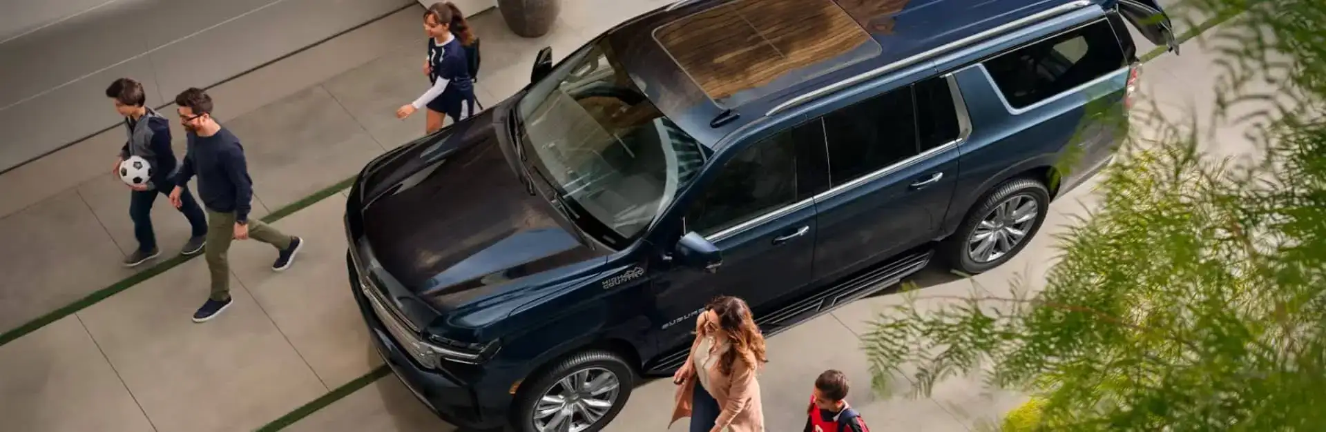 A family walking towards a Chevrolet vehicle in the driveway.