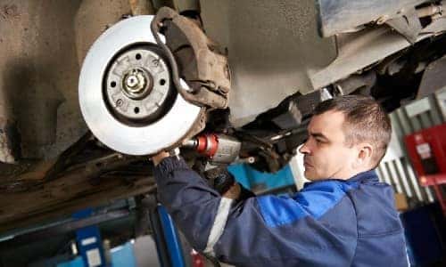 Kia Lincolnwood Brakes - mechanic - in blue - working on brakes  