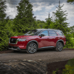 Red Nissan Pathfinder SUV driving down dirt road
