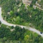 A car driving along a scenic highway with green trees and rocky cliffs