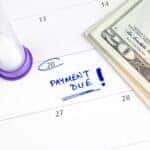 A calendar that is circled and reads "Payment Due!" next to a stack of money
